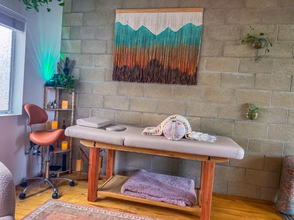 The Word of Mouth Healing Room treatment table with macrame wall hanging and candles